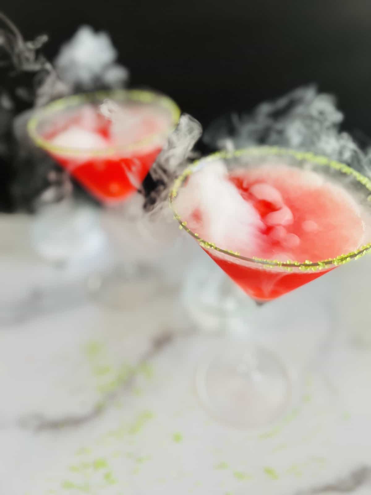 Hocus-Pocus-Cocktail-Looking-down-on-the-angle-of-the-two-martini-glasses-smoking-up-from-dry-ice-dropped-in-red-cocktail
